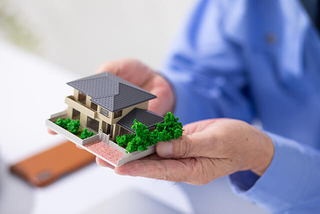 家の模型をもつ人の手