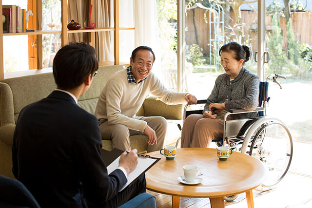 車椅子のシニア女性と相談をする夫とビジネスマン