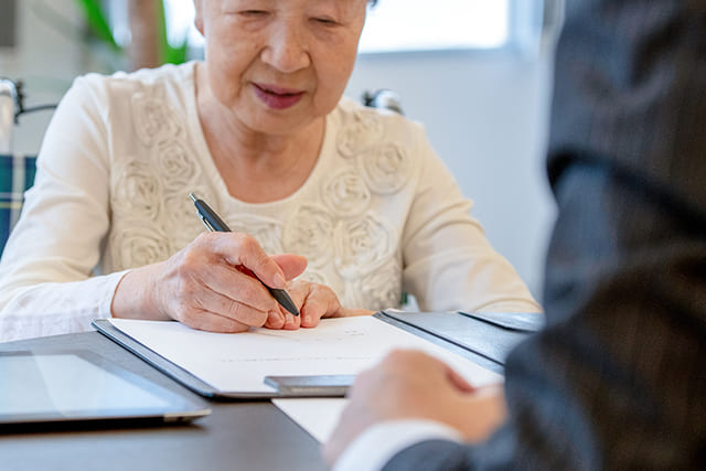 契約書にサインするシニア女性