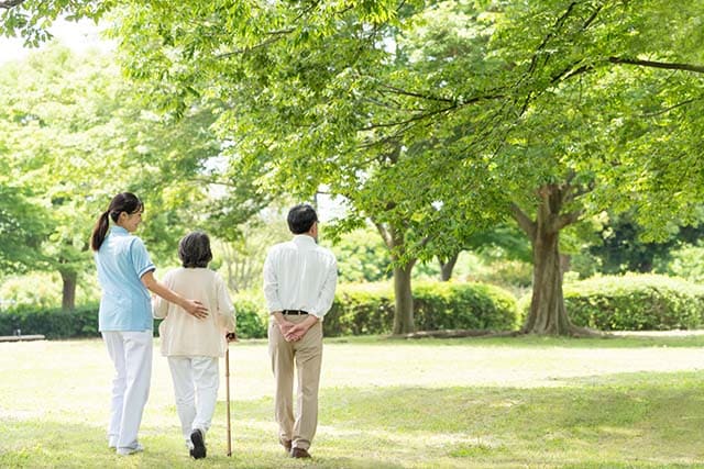 介護スタッフの付き添いで散歩を楽しむ老夫婦