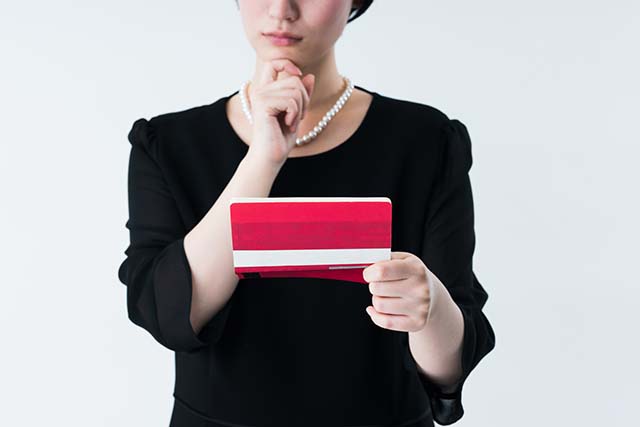 通帳を見て悩む女性