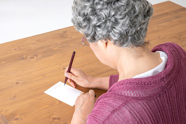 ハガキを書くシニア女性