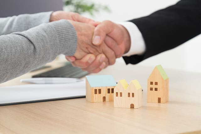 家の模型と握手する手