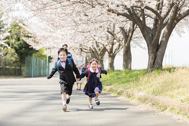 手をつないで走る小学生