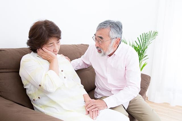 頬杖をつく女性に話しかける高齢の男性