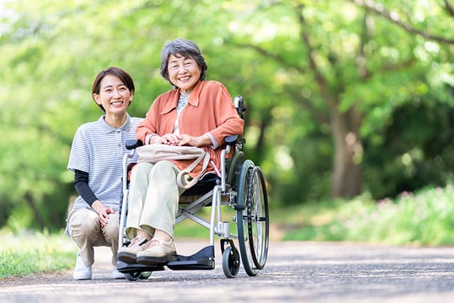 車椅子に乗った高齢者と介護する女性