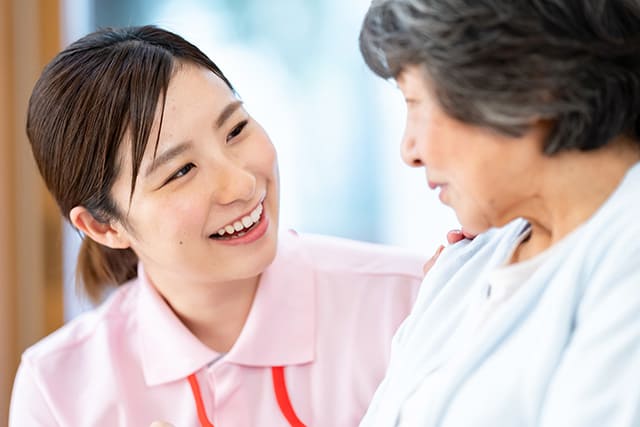 シニア女性を見て微笑むスタッフ