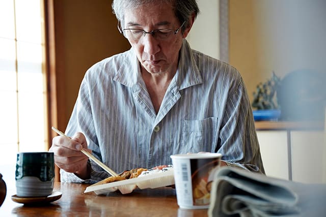 一人で食事するシニア男性