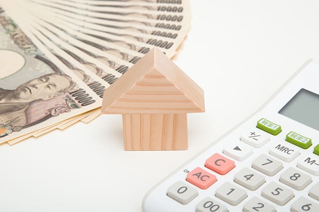 お札と電卓に挟まれた家の模型