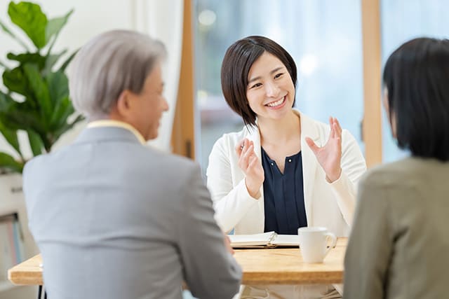 テーブル越しに会話する夫婦と女性スタッフ