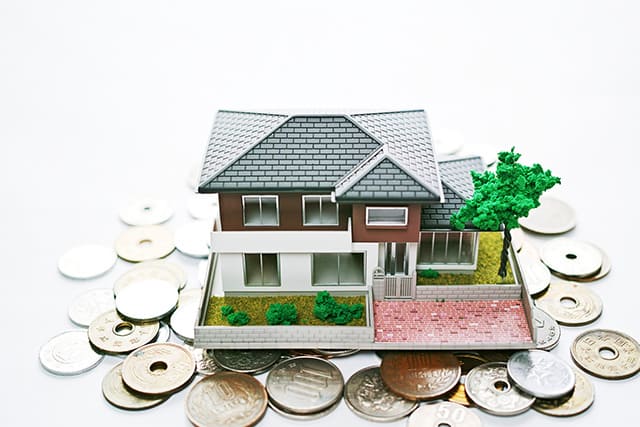 大量の硬貨の上に置かれた住宅模型