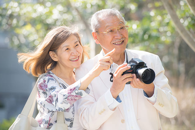 戸外でカメラを持つシニアの夫婦
