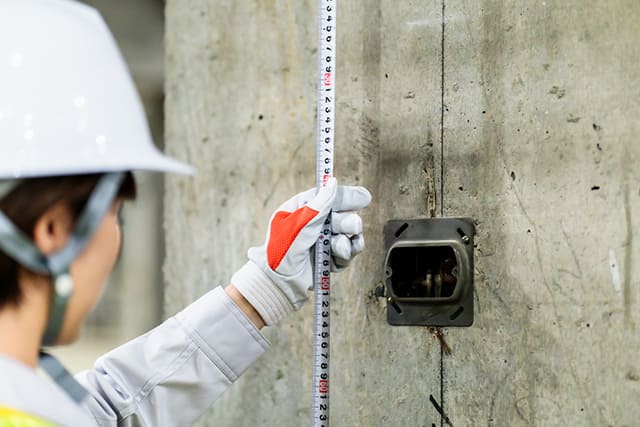 建築現場でメジャーで計測する女性作業員