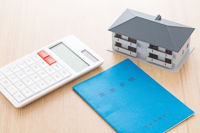 年金手帳と電卓と住宅模型