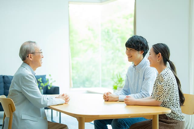 会話をする若い夫婦と高齢の男性