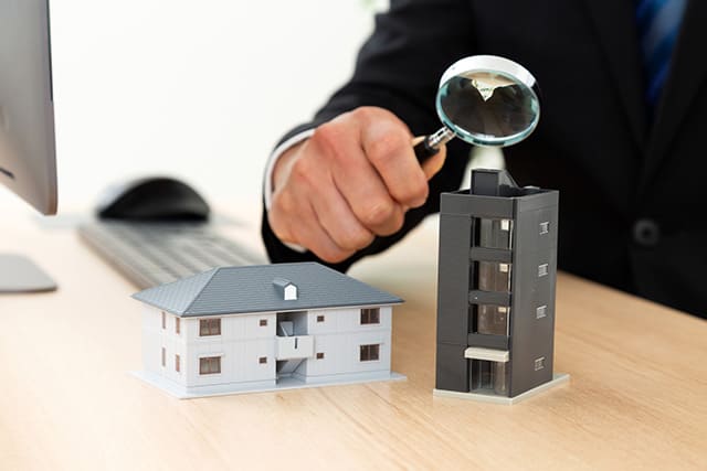虫眼鏡を持った人と家の模型