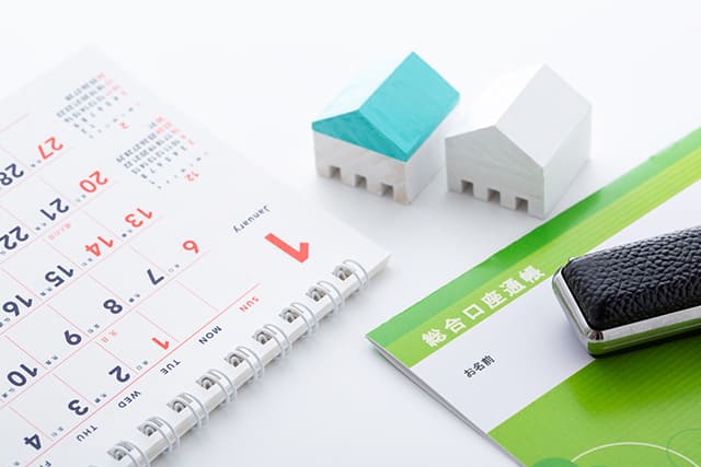 通帳と印鑑と家の模型とカレンダー