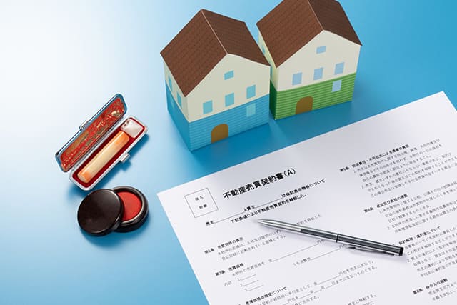 家の模型と印鑑、不動産売買契約書