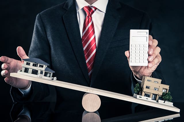 スーツを着た男性と天秤にかけられた家