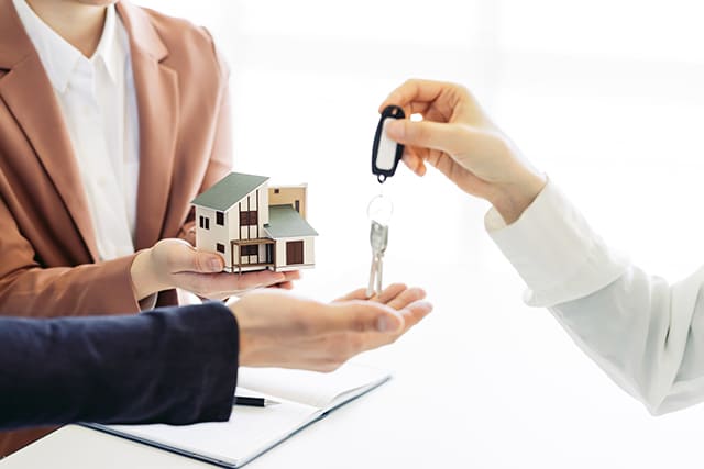家の模型と鍵を渡す人と受け取る人