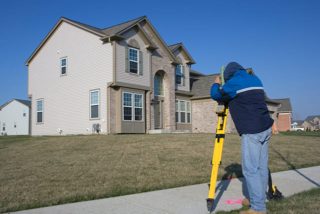 住宅と土地の測量をする人