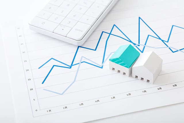 家の模型と電卓と折れ線グラフ