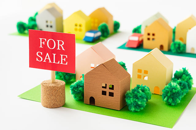家の模型と売却中の看板
