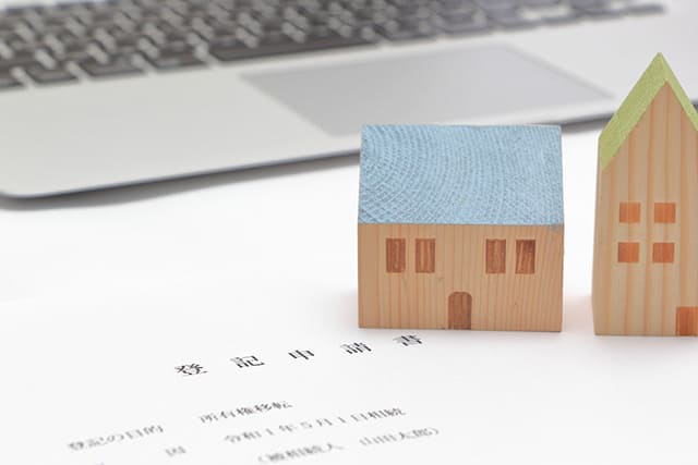 2つの家の模型と登記申告書とノートパソコン
