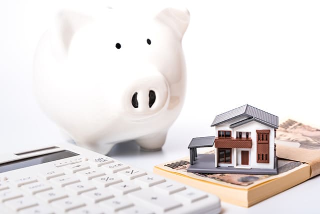 紙幣の上にある家の模型と貯金箱