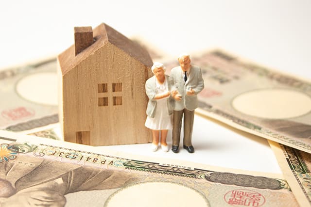 老夫婦の人形と家の模型を囲むお金