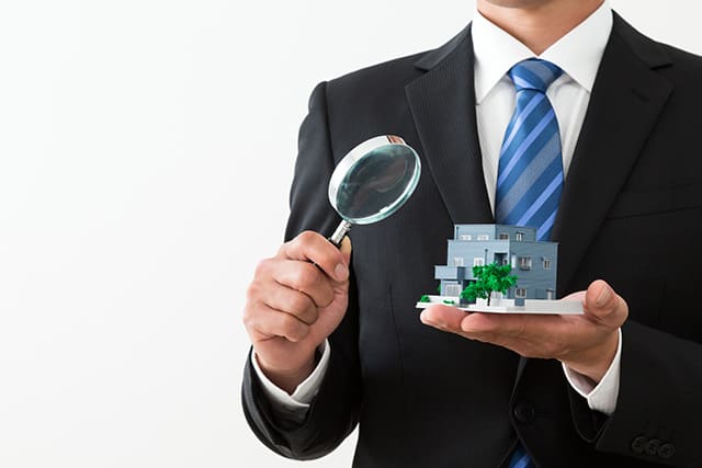 家の模型と虫眼鏡を持ったサラリーマン