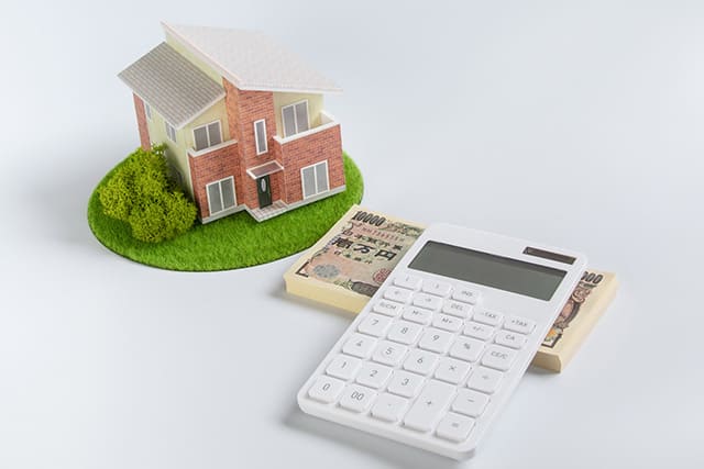 家の模型と札束と電卓