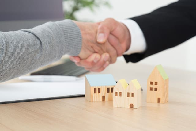 借地権付き物件の取引がまとまり握手する様子と家の模型