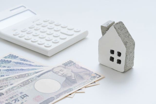 家の模型と電卓とお金