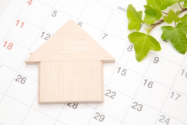 不動産売却の期限を示すカレンダーと家の積み木
