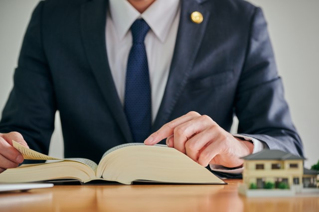 実家売却について六法全書を見て調査する担当者