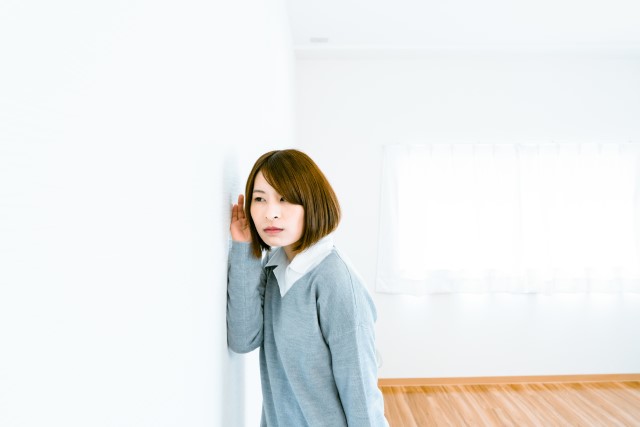 隣の部屋の生活音をチェックする女性