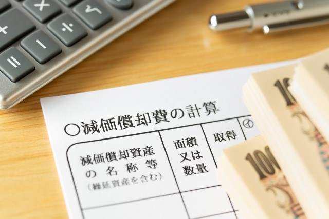 減価償却費の書類と現金と電卓