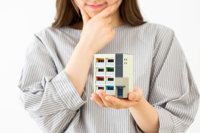 マンションの模型を持つ女性