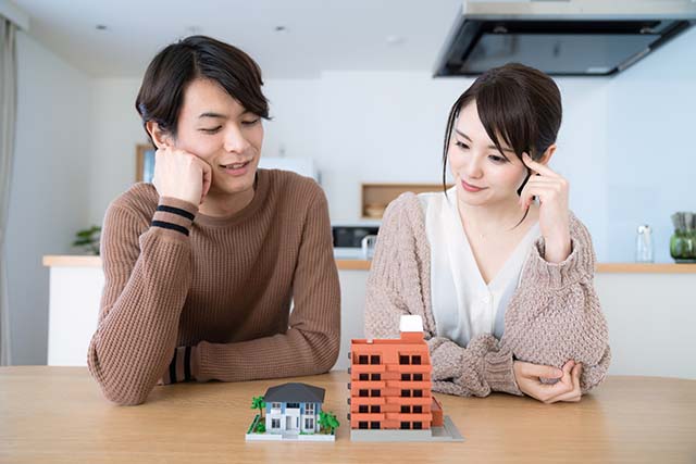 マンションの模型を眺めるカップル