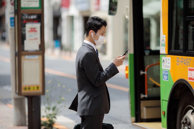 バス停でバスを待っている男性