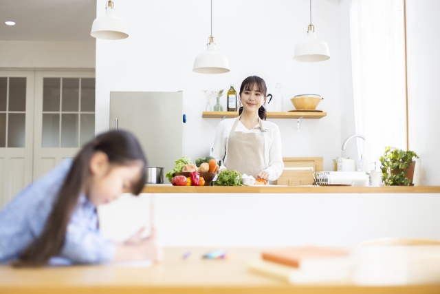 リビングにいる子どもをキッチンから見守る母親