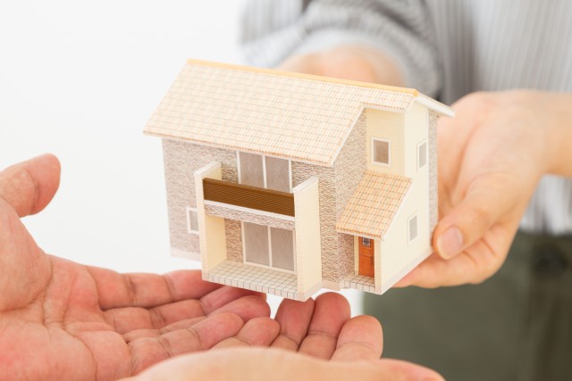 家の模型を手渡しする2人