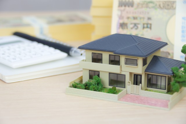 家の模型と電卓と札束