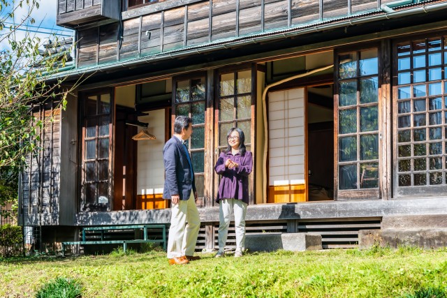 古い家の前でくつろぐ老夫婦