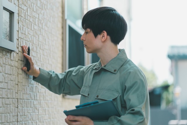 外壁の状態をチェックする作業服姿の人