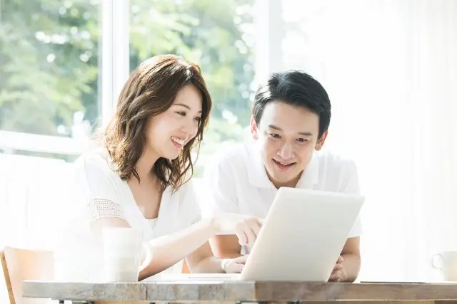 PCでパワーカップルについてリサーチする若い夫婦